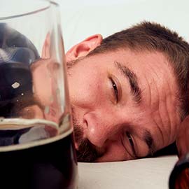мужчина лежит на кровати рядом с кружкой пива